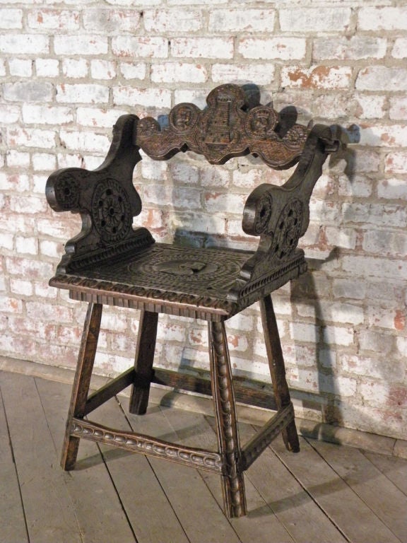 Unusual alpine armchair overall carved with interesting decoration, the back featuring a tower, the seat a romayne portrait, the shaped armrests having a wheel design, the four legs are decorated with chip-carving, connected by conforming box