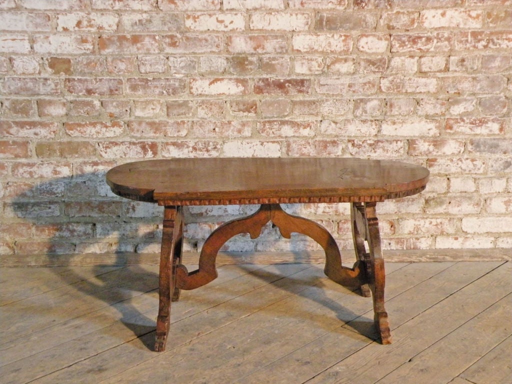 Rare and adorable small low table of unusual shape.
The oblong top with rounded ends and dentil edge supported by lyre-form ends, joined by a wavy stretcher.
