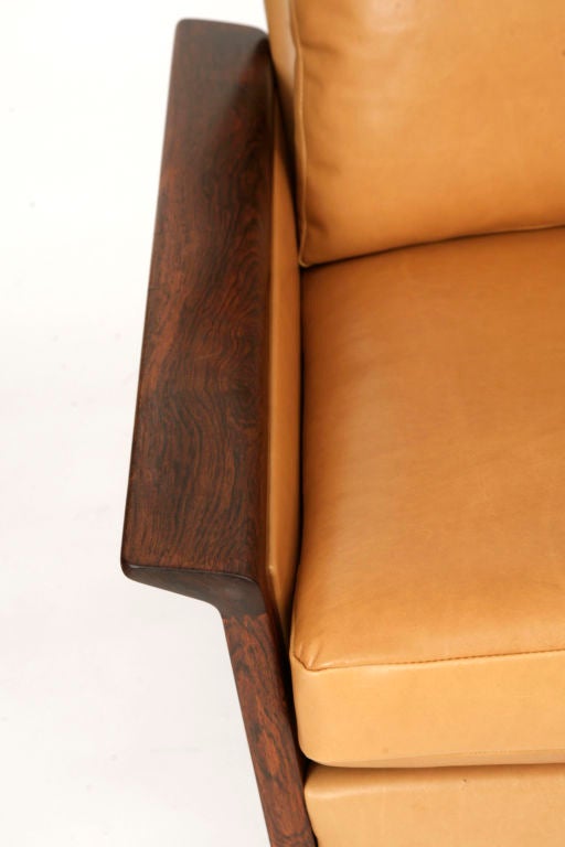Rosewood and leather sofa by Hans Olsen circa early 1950’s. Sofa features exotic Brazilian rosewood with beautiful black graining and flared arms. The upholstery is done in a supple buttery smooth leather french seaming to the upholstered frame and