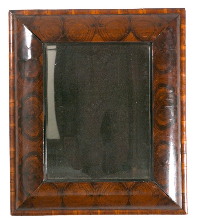 A William and Mary period cushion mirror with oyster-veneered frame and an ebonized, reeded molding immediately surrounding the mirror plate. With the original mirror plate which retains the original mercury lining. A large example of this form and