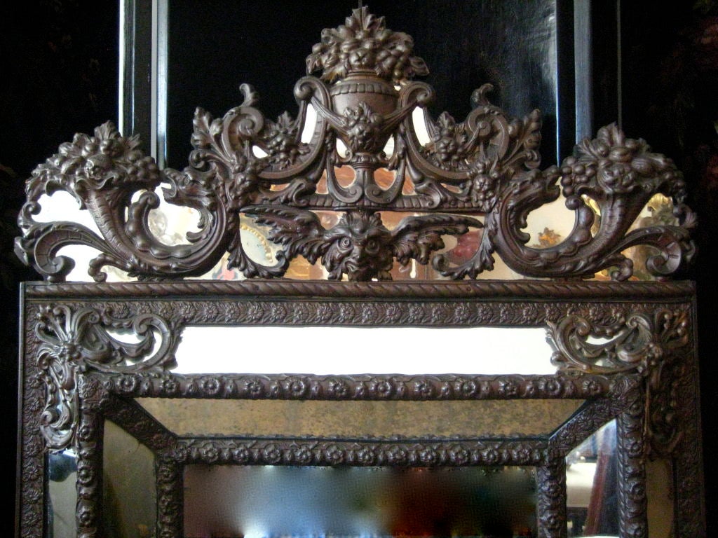 Miroir en laiton repoussé du sud de la France. La façade est composée de neuf sections de miroir, entourées de reliefs en laiton martelé, avec un dos en bois.