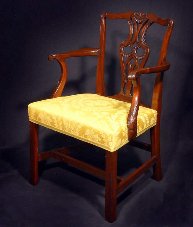 Comprising six side and two armchairs, each with serpentine foliate carved crest rail above pierced vasiform backsplats centered by solid stiles; the overupholstered seat raised on square legs joined by stretchers.