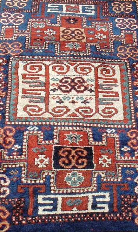 A wonderfully graphic village rug in primary colors with accents of green, contrasted by an ivory 