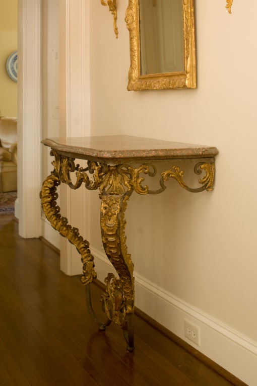 An important and rare French Louis XV period, wrought iron and gilt metal console table.  This console table is an extremely unusual combination of high rococo design interpreted in what was considered an unusual, and even experimental, material in