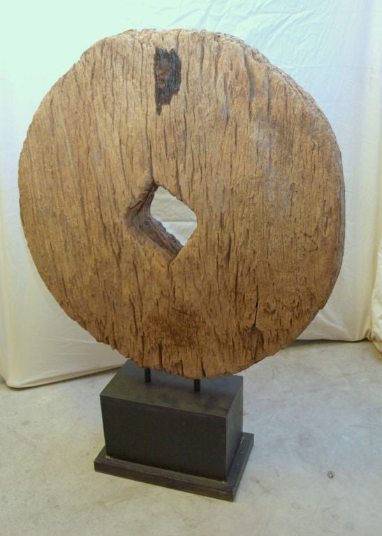 This antique wheel was hand carved from a single log.  With the use of primitive tools combined with the age of the wood, it remains in great, natural rustic condition. It has been mounted on a custom heavy duty steel base (painted black), that