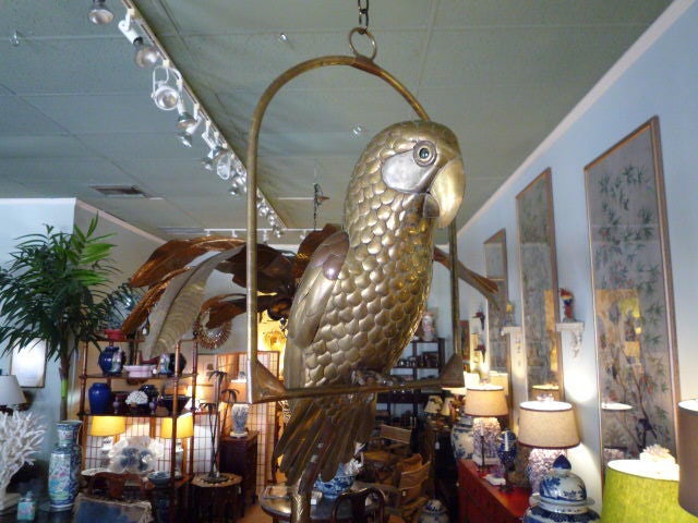 A well made, large brass and copper decorative parrot on a hoop, with great patina and glass eyes, in the style of Bustamante.