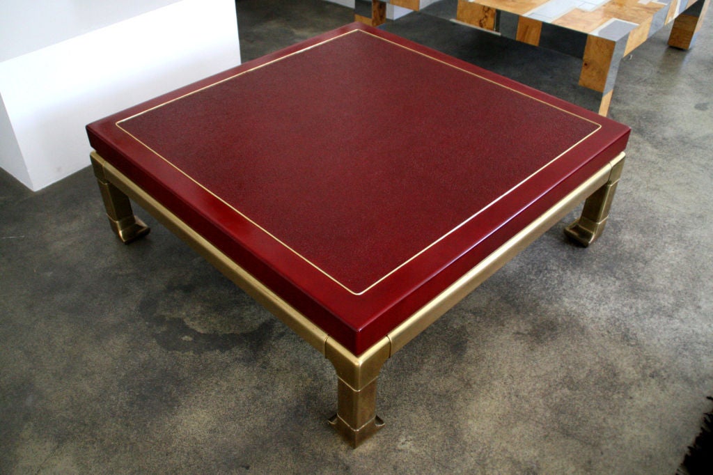 Stunning coffee table designed by Mastercraft, c. 1960's. Newly refinished top in a rich blood red. Brass inlaid detail through top, with solid brass base and legs.