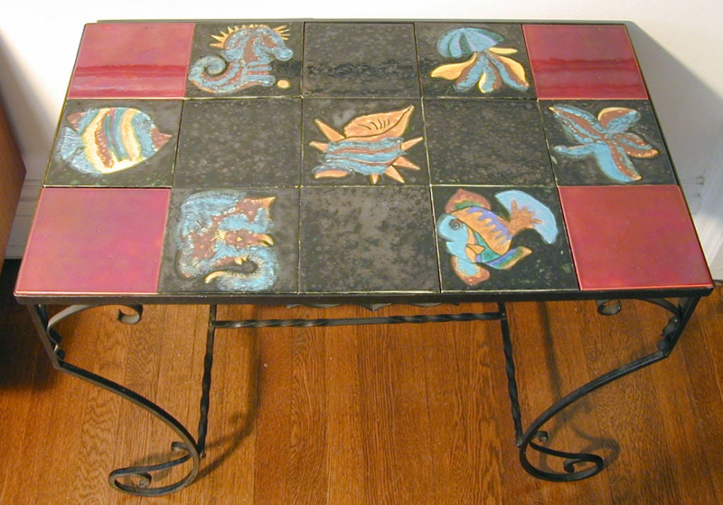 This rare Moderne wrought iron table is topped with rare, 6-inch tiles in a marine motif produced at Quimper in France. A wide range of sea life is colorfully and joyously evoked, including an angelfish, seahorse, jellyfish, starfish and stingray.