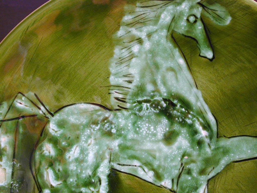 Ce très beau plateau, émaillé dans de superbes tons de jade, de mousse et de blanc, représente un cheval au pas de charge.  Il est marqué 