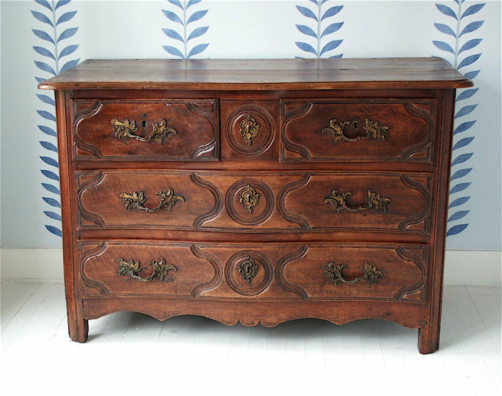 Stamped by the registered ebeniste Jean-Baptiste Simoneaux, an exceptional walnut five-drawer (one secret) commode; with its original fire-gilded bronze drawer pulls and escutcheon plaques. A 'Provincial' commode made by a Parisian Eboniste, during