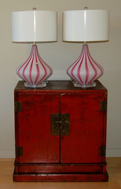 These beautiful magenta and white circus tent lamps have a satin finish to the glass, known as acidato. Mounted on a simple Lucite base to compliment and enhance the glass.

The lamps stand 22 inches high from tabletop to socket top. As shown, the