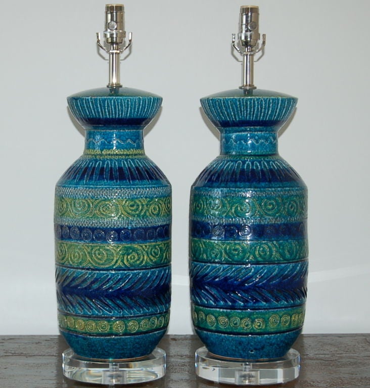 Beautiful pair of Bitossi trademark GREENS and BLUES ceramic lamps, imported by Balboa in the mid 20th century.  Completely rewired with nickel plated solid brass hardware and mounted on Lucite bases.

The lamps stand 25 inches tall to their