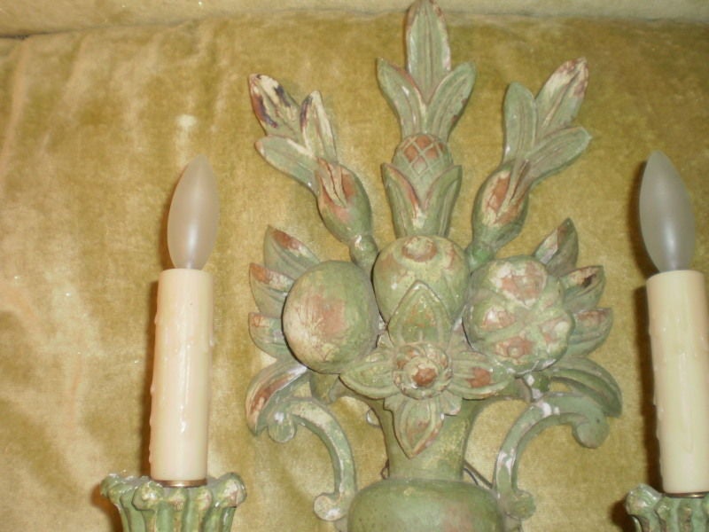 Pair of Italian painted carved wood sconces depicting a floral basket. These beautiful Italian two-light sconces in a beautiful shade of light green have been newly wired for U.S. market with polywax candle sleeves, circa 1920. They easily could be