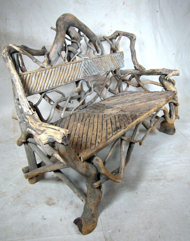 Weathered American rustic Adirondack loveseat bench made of twig and rootwood  with decorative design.