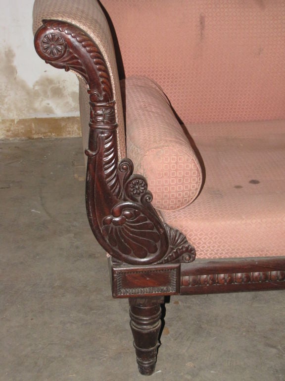 19th Century Empire style Sofa with a carved top rail and scrolling arms, raised on turned circular tapering legs.
