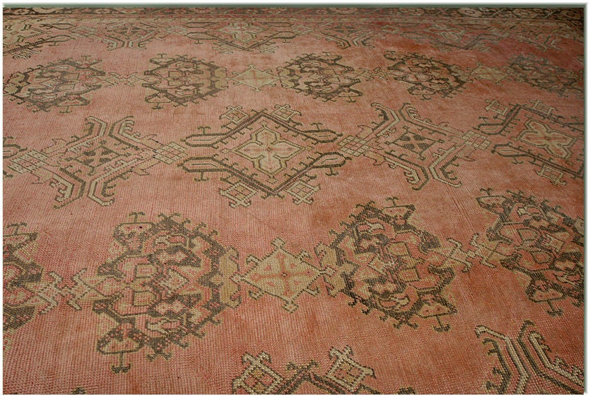 MEDALLION PATTERNED OUSHAK WITH ALL OVER DESIGN WITH SOFT SALMON BACKGROUND & BROWN AND GOLD TONES.   CIRCA 1900.<br />
11'2