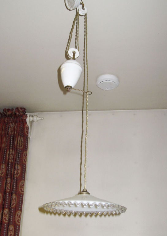 Ceiling light with glass shade and ceramic weight that allows the lamp to be pulled up and down as needed. 
These lamps are traditionally used in dining/kitchen above the table.