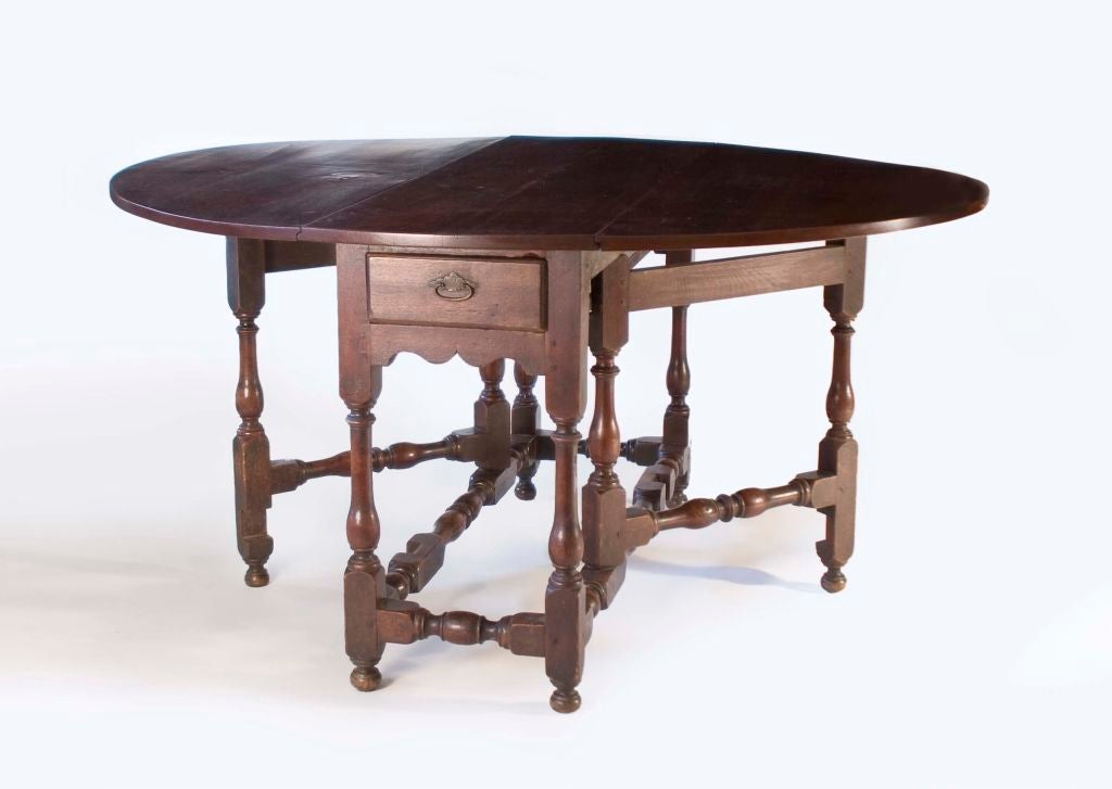 This gateleg table has an oval top with good turnings and stretchers terminating in ball feet. The table width is 17.75