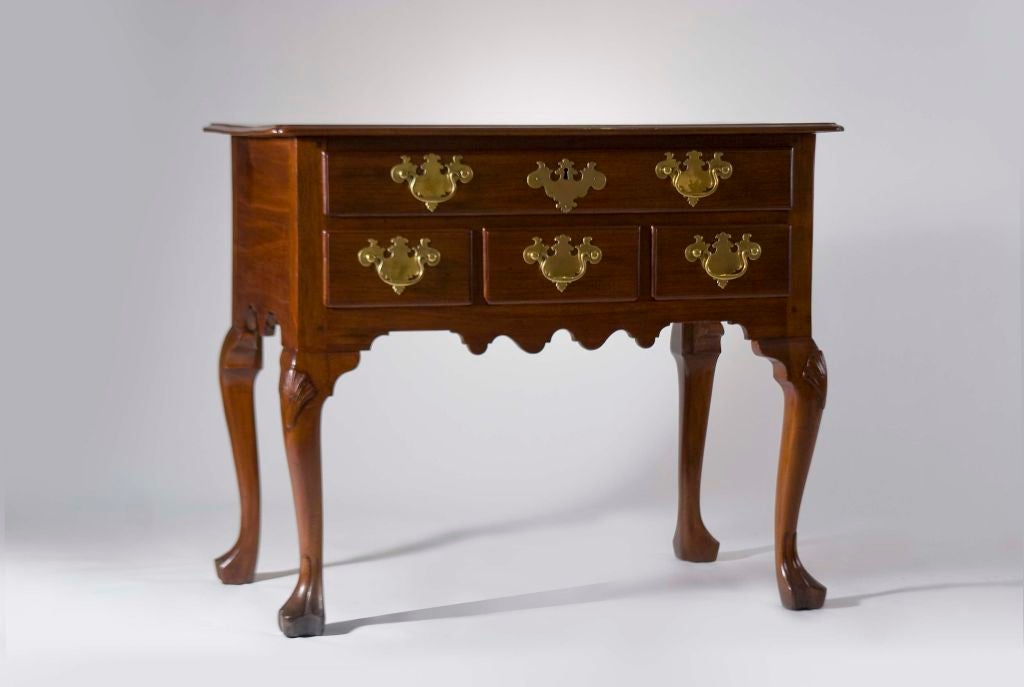 This lowboy has a nice finish with a molded top with notched corners, scalloped aprons, cabriole legs with shell carved knees and stocking feet. It has one drawer over three.