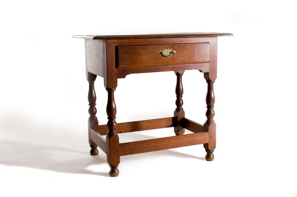 Diminutive in size, this table has a molded top with a single drawer over nicely turned legs, stretchers and ball feet.