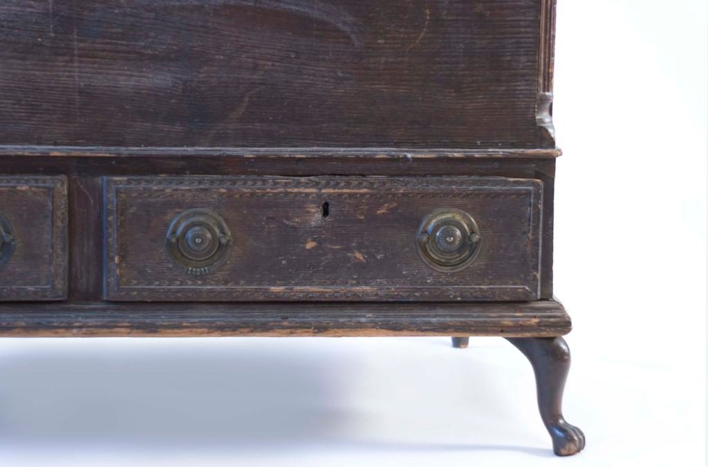 This blanket chest has an old varnish finish with fluted corners, a mid molding over three chip carved drawers, iron strap hinges, base molding over unusual short cabriole legs terminating in claw and ball feet in front and turned ball feet in the