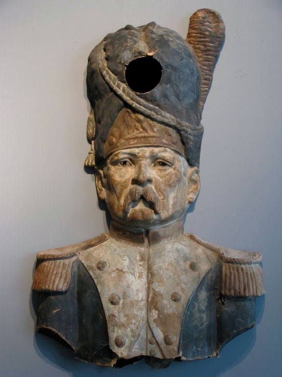 An ominous character from a midway carnival game, original surface dry paint, papier mache with wood backing, done in relief to hang on a wall or post for children to throw balls or sand filled bags at the hole in the top of his Hessian mitre cap.