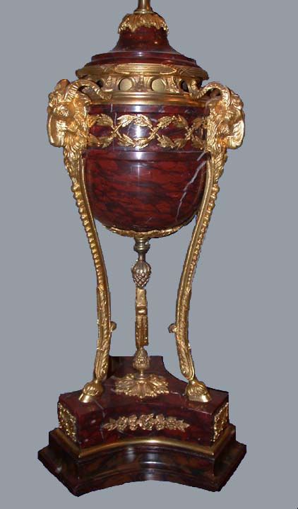 Pair of red griotte de cambon marble cassolettes supported on gilt-bronze ram's head topped tripod legs leading to cloved feet on marble tripod base decorated with gilt-bronze banding and foliate motifs,later fitted as lamps with custom trimmed