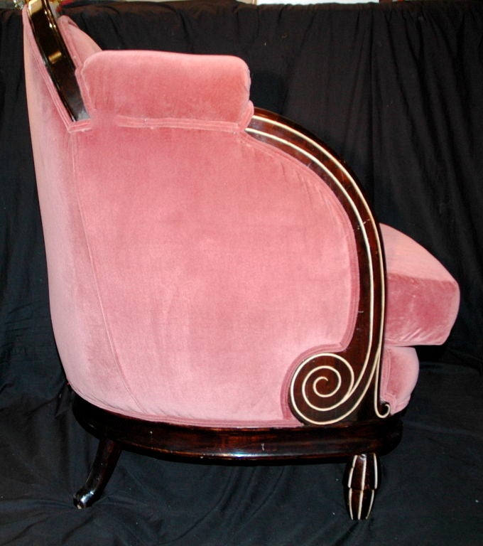 Featured is a pair of Art Deco Cigar Smoking, music listening, library reading club chairs. The chairs have a wood frame with swirl detail. A great feature is the high arm rests. The fabric is a dusty rose velvet worn in enough to delight the