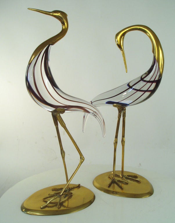 a wonderful pair of Italian murano glass and brass standing egrets. beautiful clear glass with purple threads. very well made and in mint condition. marked made in italy