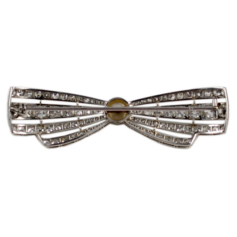 Fine and rare Art Deco diamond and natural Oriental pearl bow pin, slightly arched to resemble a tied bow with simple graduated linear design of fine quality diamonds.
