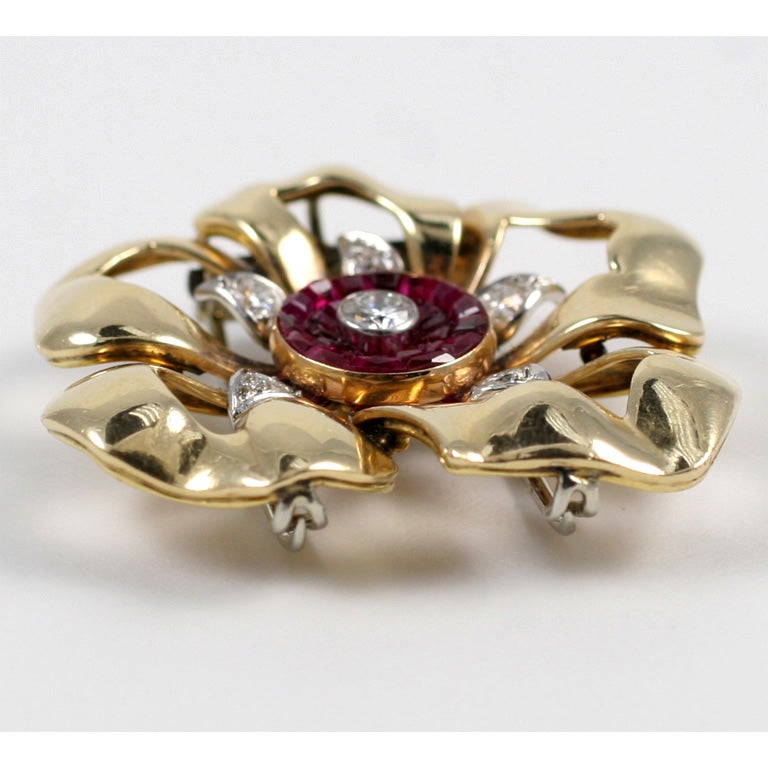 Cartier New York Gold Ribbon Pansy set with a center diamond surrounded by invisibly set rubies and diamond set leaves. The pin has a platinum double prong clip, designed for easy wear.