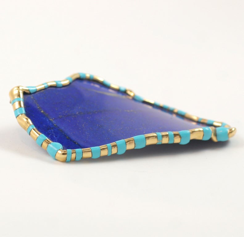 A stunning brooch of rich blue lapis lazuli is sensuously  curved, and bordered by a conforming gold frame accented with turquoise.