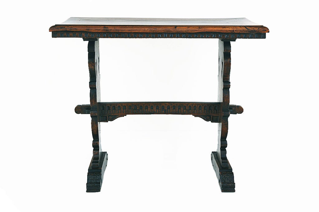 the rectangular top having a conforming alternating dark and light fruitwood and walnut inlay and an overhanging dentile molded edge, supported by carved handled urn shaped supports and resting on elongated carved bracket feet, joined by a dentile