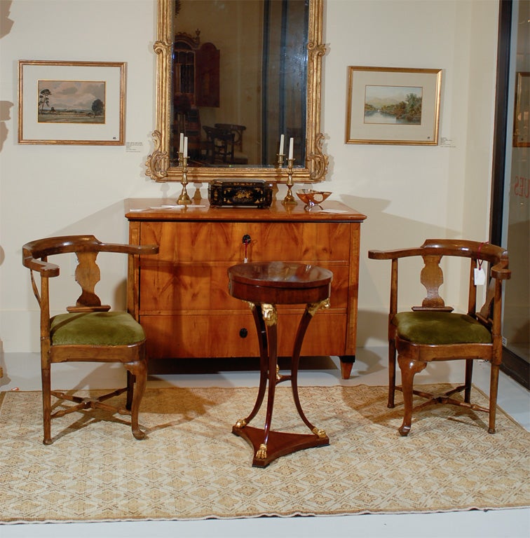 A very fine cherry wood work table of tripod form, the circular top opening to a fitted interior and concealed mirror, resting on elegantly shaped legs, each crowned with a parcel gilt lion’s head and ending in a parcel gilt paw foot, the three legs
