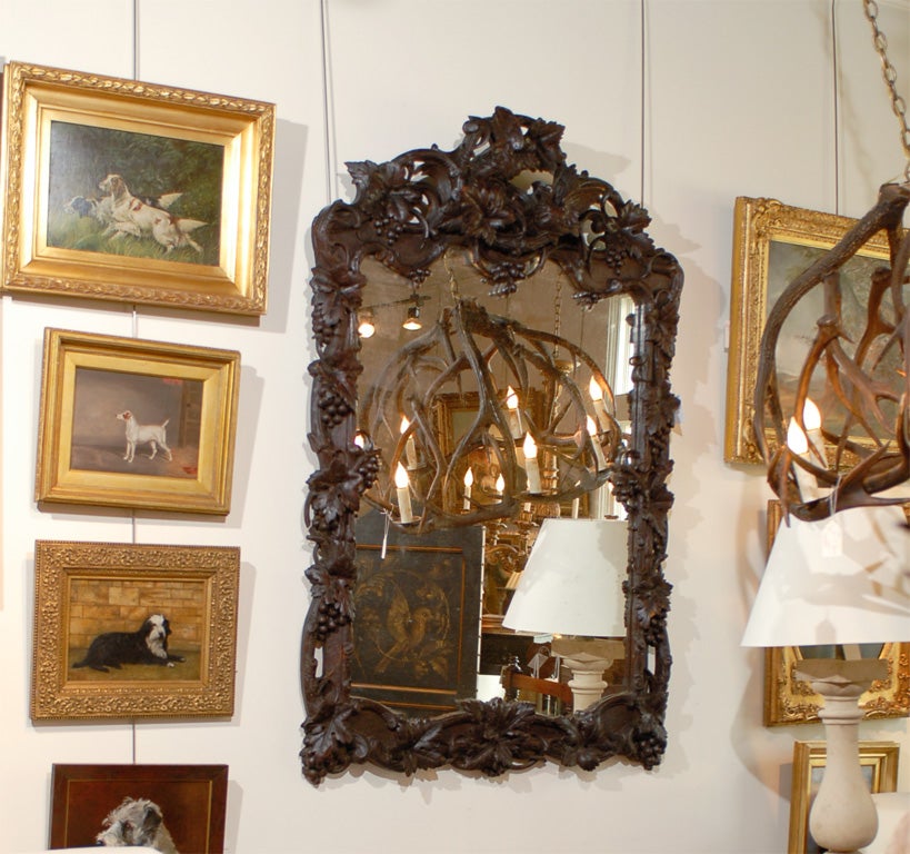 This large late 19th century French mirror is set within a rectangular carved Black Forest style crested wooden frame. The intricate decor is composed of beautifully detailed openwork intertwined vines with leaves and grapes while a bird with its