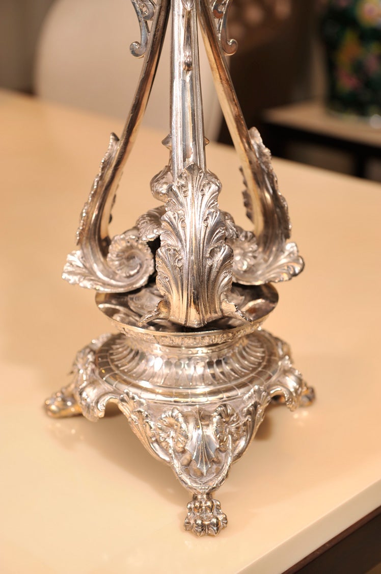 Silver plated epergne with four scalloped bowls on heavily chased stand with scrolls and leaves on three paw feet.