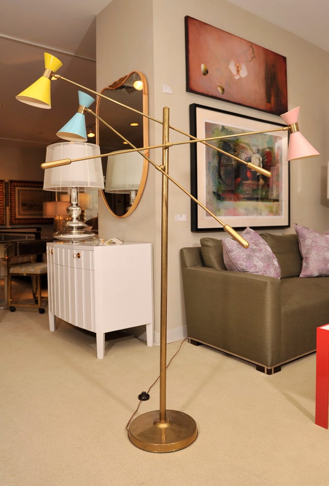 Three-light brass floor lamp with yellow-pink-blue metal shades.