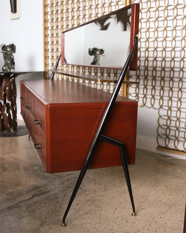 The swivel mirror above a fixed glass shelf trimmed in brass, over a mahogany case with six drawers with brass pulls, resting on an iron geometric Stand- can be sold separately- note height 1 oi overall to top of mirror- height 2 is to top of wood