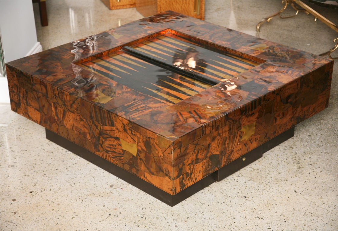 The copper and brass patchwork clad frame with an inset backgammon table on an ebonised base with drawer