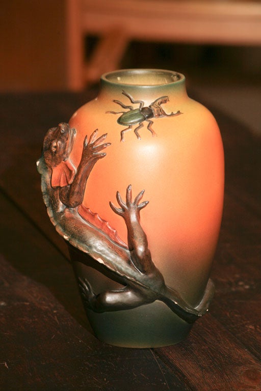Vase by Ipsen pottery factory, of Denmark, c 1920's, in distinctive orange hue, depicting a salamander chasing a large bug.