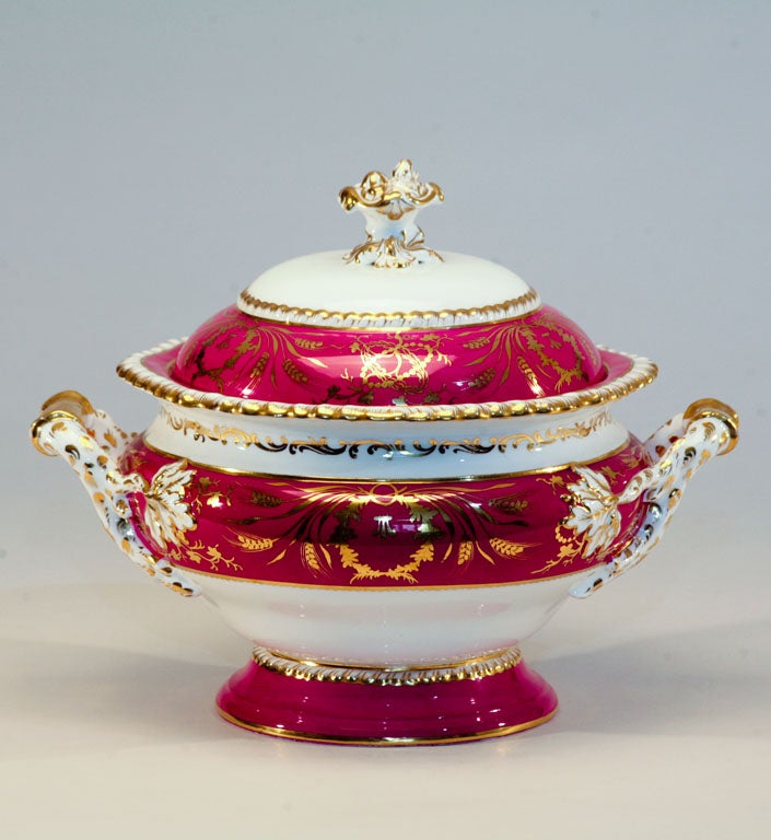 Impressive English hard-paste round soup tureen with raspberry enamel ground and gold trim. Elaborate molded leaf finial, gadroon edges and wheat sheaf gilded overlay decorates this vibrantly colored tureen. A wonderful centerpiece and of course,
