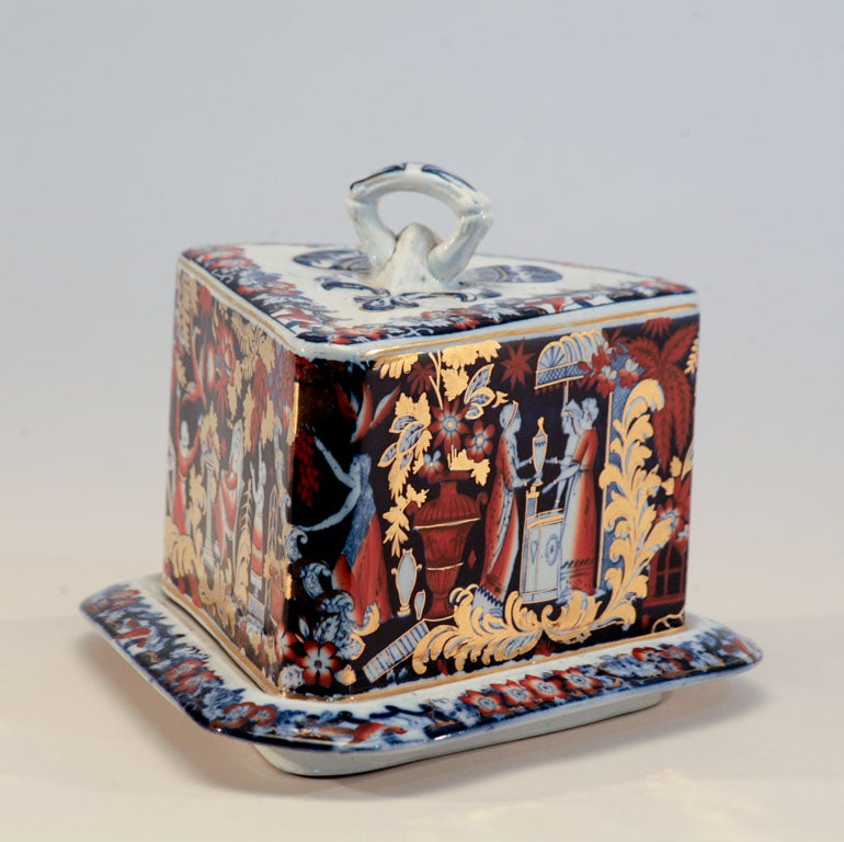 This large triangular form ironstone porcelain cheese wedge features all-over decoration with blue and white transfer. Hand colored in an Imari palette of bittersweet orange and cobalt blue and further decorated with gold overlay. Decorated on all