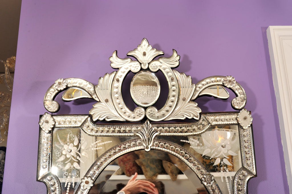 A rectangular French Venetian mirror with mirrored frame having beveled glass in sections surmounted by crest with mirrored decoration.