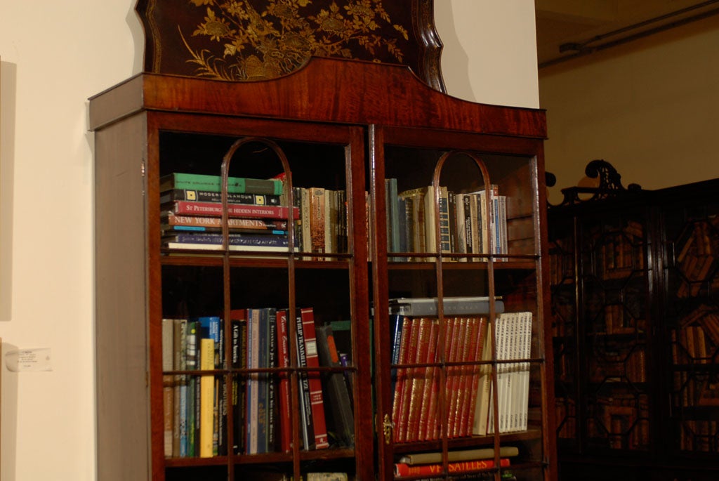 An unusual mahogany secretaire-book cabinet, the upper section with glazed doors with central arched mullions, the lower section consisting of a tambour-enclosed writing surface with adjustable document shelf and multiple small drawers with original