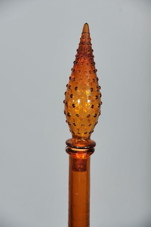 An amber glass bottle in an elegant shape with beading detail throughout body and on top; made by Guildcraft Italy with original foil label. A beautiful, delicate piece that provides a warm accent to any room.