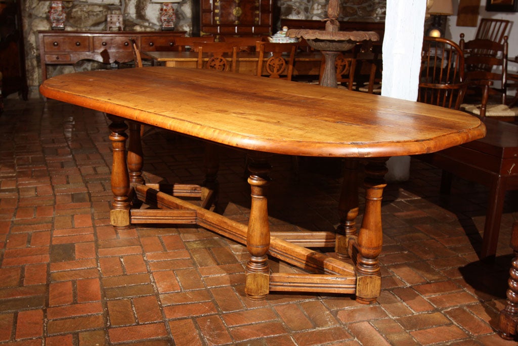 Large, cherry oblong table on unique six-leg base with turned pilasters and reeded stretchers. The 3/4 inch thick top is bolstered at the bull-nose edge to appear 1 1/2 inches thick, effortlessly balancing the visual weight of the base and rendering