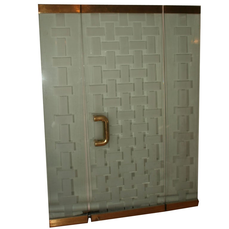An American midcentury entryway with an etched glass basketweave pattern and brass handle and frame.