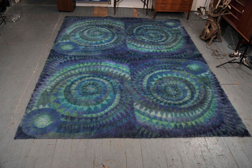 Woven wool rug with a beautiful mixture of blues and light greens in spiral design divided into quadrants.  Located at LV2, 113 Stanton St., (212) 358-8000