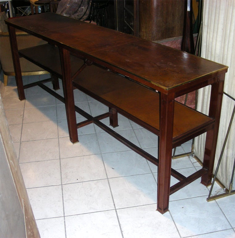 Large 1940s console table by Jacques Adnet  in mahogany with two leather shelves and gilt bonze elements.