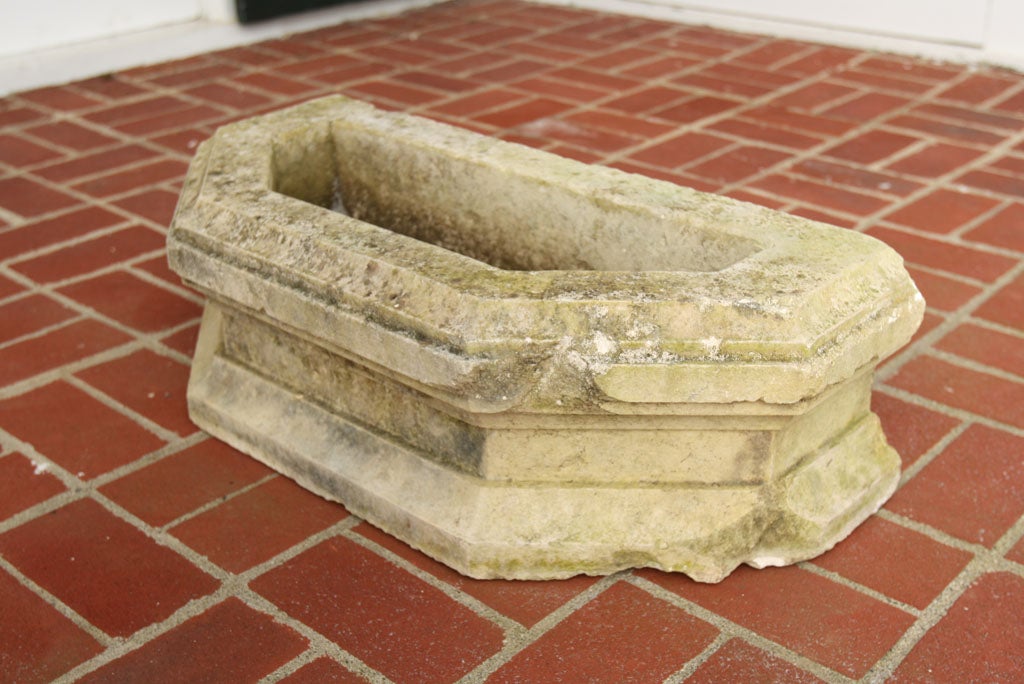 A carved stone D-shaped basin or planter.